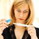 Woman holding a pregnancy test, looking tense, concentrating and shocked