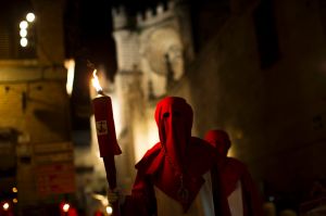 Hooded penitents from "Cristo de los Angeles" brotherhood hold torches as they take part in a traditional annual Holy ...