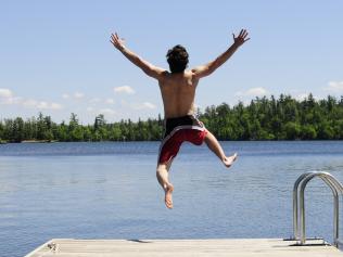 Young man running off dock on beautiful summer's day