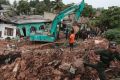 Sri Lankan army soldiers and rescue workers stand near buried houses.