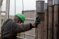 A worker positions a drill bit high up on the derrick of a drill rig.