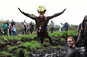 A man dressed as the Pope jumps into a pool of mud as competitors take part in the annual McVities Mud Madness 8km cross ...