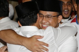 Anies Baswedan hugs his running mate Sandiaga Uno during a press conference in Jakarta. Early counts showed a decisive ...