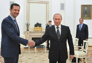 In this file photo taken on Tuesday, Oct. 20, 2015, Russian President Vladimir Putin, center, shakes hand with Syrian President Bashar Assad as Russian Foreign Minister Sergey Lavrov, right, looks on in the Kremlin in Moscow, Russia.