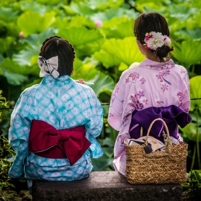 Two young ladies in festive outfits share a quiet moment by a field of water lilies. Taken in Tokyo at a floating ...