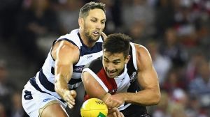 Billy Longer of the Saints handballs while being tackled by Harry Taylor of the Cats 