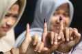 Women show their ink-stained fingers after voting during the runoff election in Jakarta.
