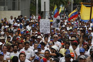 People protest in homage to the at least 20 people killed in unrest generated after the nation's Supreme Court stripped congress of its last powers, a decision it later reversed, during a silent march to the Venezuelan Episcopal Conference in Caracas, Venezuela, Saturday, April 22, 2017. The sign reads in Spanish "This is the dictatorship that Chavez and Fidel dreamed of."