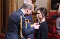 Fashion designer Victoria Beckham, right, receives her OBE from Britain's Prince William, the Duke of Cambridge during ...