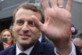 Centrist candidate Emmanuel Macron waves to supporters as he leaves his house.
