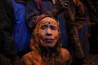 A Nepalese, face smeared with vermilion powder, watches a chariot being carried during Sindoor Jatra festival in ...