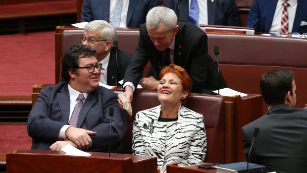 Senator Malcolm Roberts offers a bag of cashews to Senator Pauline Hanson and George Christensen during the opening of ...