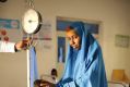 An emaciated Somali boy is weighed next to his distraught mother.