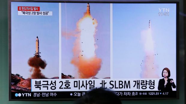 A man watches a TV news program showing photos published in North Korea's Rodong Sinmun newspaper of North Korea's ...