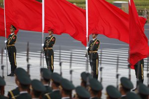 In this Monday, Oct. 31, 2016 photo, members of an honor guard march past their comrades holding flags as they prepare for a welcome ceremony for visiting Belgian Prime Minister Charles Michel outside the Great Hall of the People in Beijing