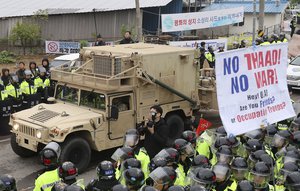 U.S. military vehicle moves past banners opposing a plan to deploy an advanced U.S. missile defense system called Terminal High-Altitude Area Defense, or THAAD, as South Korean police officers stand guard in Seongju, South Korea, Wednesday, April 26, 2017.