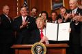 President Donald Trump holds up the signed executive order in Washington on Wednesday.