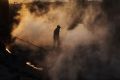 A Chinese labourer walks in steam next to a furnace and cooling pit at an unauthorised steel factory on November 4, 2016 ...