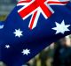 Crowd members wave an Australian flag as marchers go past on Swanston St during the ANZAC day march in Melbourne 2003.