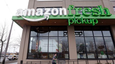 An Amazon worker wheels back a cart after loading a bag of groceries into a customer's car at an AmazonFresh Pickup ...