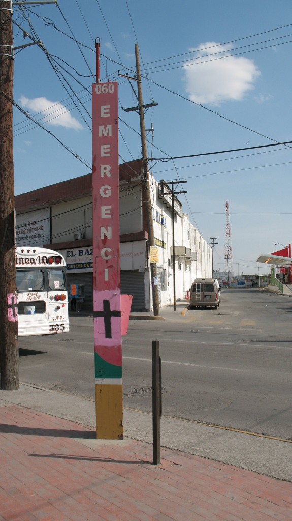 In 2015 the iconic pink and black crosses still stand in Juarez. This cross is painted on a pole for the 060 Emergency line. Coincidentally, a bus from the Number 10 line that passes  by Sagrario's house was parked nearby.   Photo Credit: Bob Chessey 