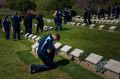 A NSW student on the schools tour of Gallipoli kneels in front a grave stone at Shrapnel Valley Cemetery. 