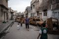 A man walks with his children past burnt-out cars in a street in west Mosul earlier this month.