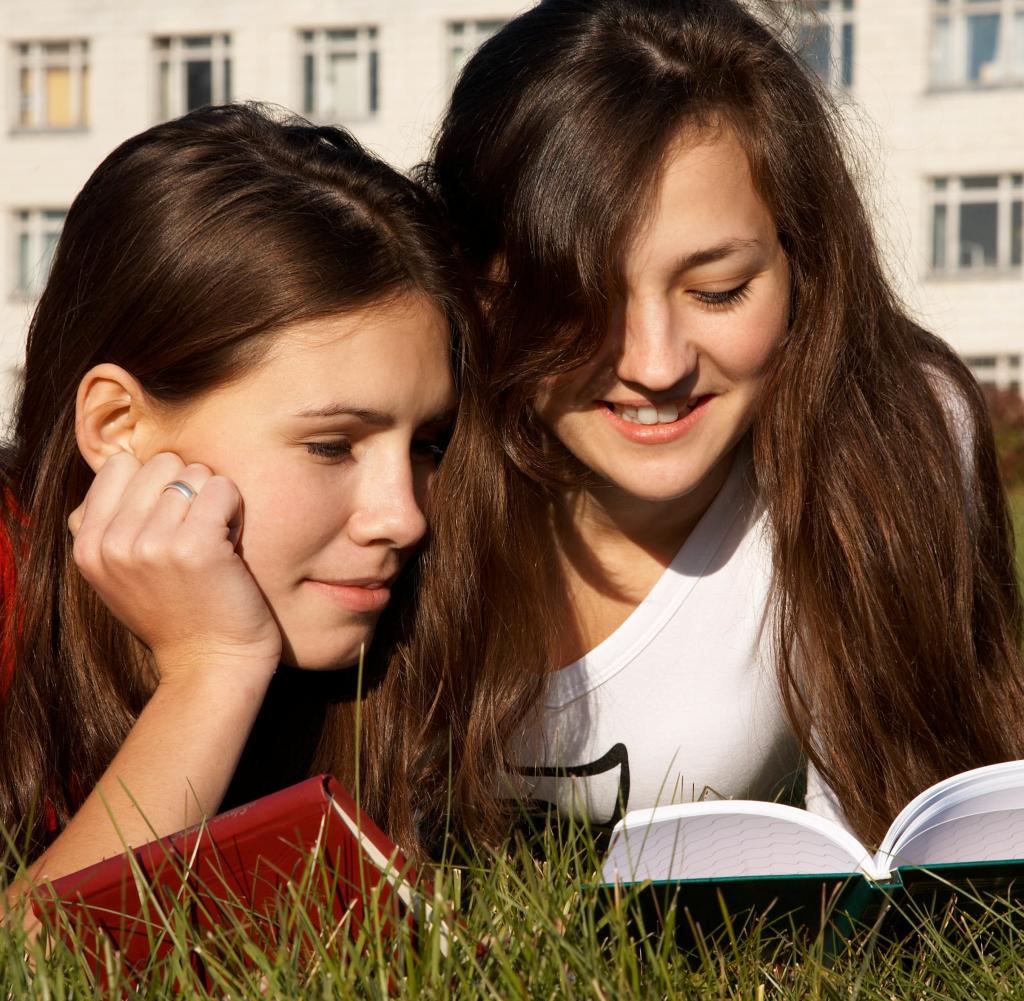 Student girls reading the books on the lawn near University