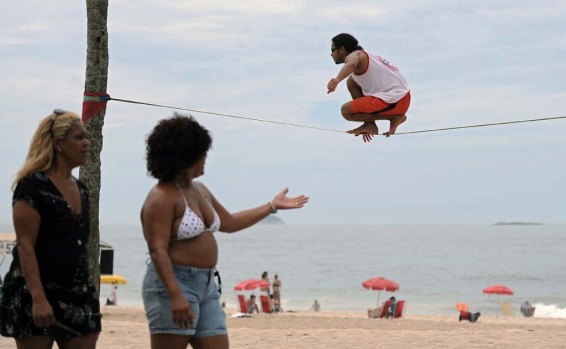 A man balances on a rope tied to two palm trees at Ipanema beach in Rio de Janeiro.