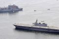 Japan's helicopter carrier Izumo, foreground, sails by a US supply ship, top left.