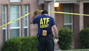 An ATF agent lifts crime scene tape outside the scene of two murders Thursday morning, Aug. 8, 2013, in DeSoto, Texas. Four people were killed at two different locations in South Dallas County and the suspected shooter is in police custody.