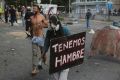 A demonstrator holds a sign the reads in Spanish "We are hungry" during clashes with the Bolivarian National Guard in ...