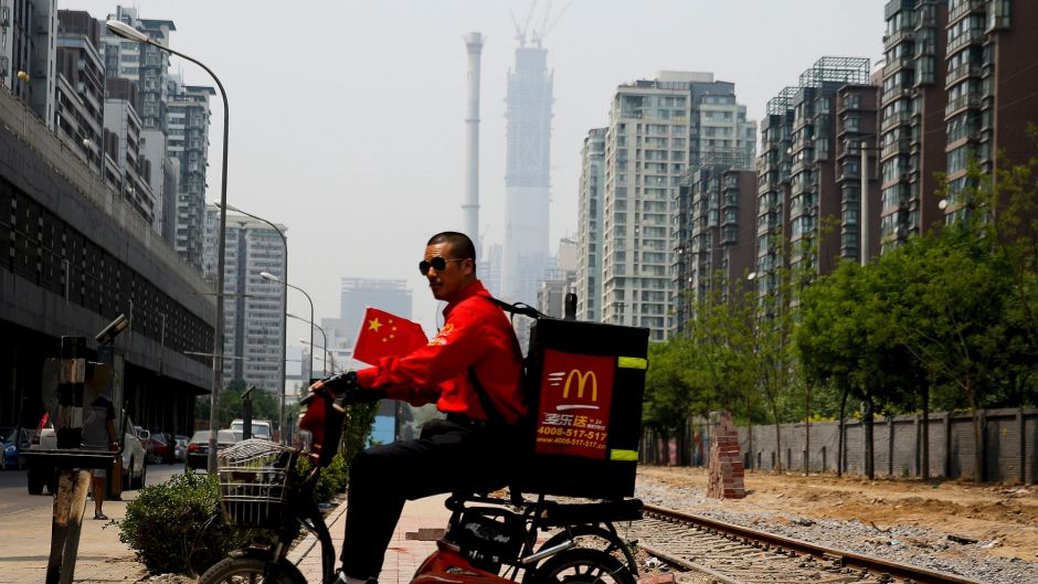 A McDonald's delivery man rides past an abandoned railway track near residential buildings in Beijing, Tuesday, May 2, ...