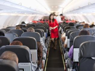 Passengers inside the cabin of a commercial airliner during flight. Shallow depth of field with focus on the seats in the foreground.