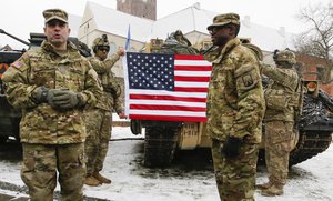 U.S. Army soldiers hold an American flag as they attend the official welcoming ceremony of the U.S. troops in Zagan, Poland, Saturday, Jan. 14, 2017