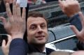 Emmanuel Macron greets well-wishers as he leaves the polling station.
