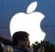 FILE - In this Friday, May 13, 2016, file photo, a man uses his mobile phone near an Apple store in Beijing, China. ...