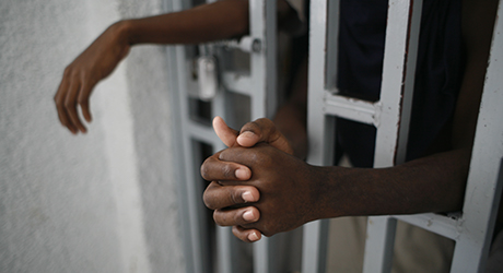  Boys hands reach through the metal bars of a prison cell © UNICEF/ ROGER LEMOYNE