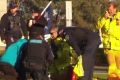 Emergency services treat the protester on the lawn of Parliament House in Canberra.