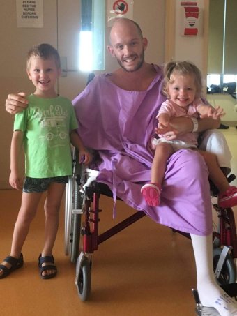 Glenn Dickson sits in a wheelchair surrounded by his kids