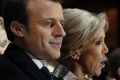 Incoming French President Emmanuel Macron and his wife Brigitte Macron sing the national anthem after he delivered a ...