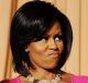 First lady Michelle Obama flexes her arms in response to a joke about her habit of wearing sleeveless dresses during the ...