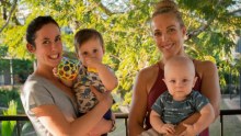 Two women and their children smile for a family-style photograph.