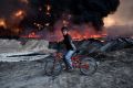 A boy pauses on his bike as he passes an oil field that was set on fire by retreating IS fighters ahead of the Mosul ...