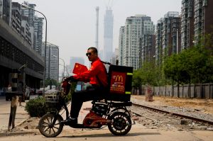 A McDonald's delivery man rides past an abandoned railway track near residential buildings in Beijing, Tuesday, May 2, ...