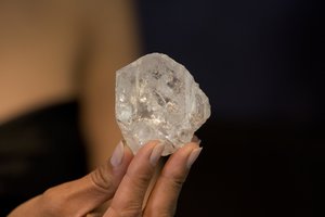 A model poses for photographs holding up the largest gem-quality rough cut diamond discovered in over 100 years, the 1109-Carat “Lesedi La Rona” at premises of the Sotheby's auction house in London