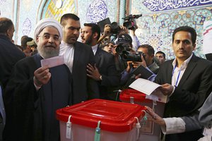 In this photo released by official website of the office of the Iranian Presidency, President Hassan Rouhani holds his ballot while voting for the presidential and municipal councils election at a polling station in Tehran, Iran, Friday, May 19, 2017.