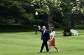 US President Donald Trump waves while walking towards Marine One with wife Melania Trump.