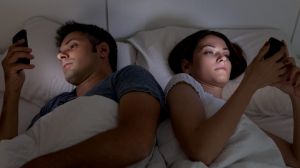 Young couple with smartphones in their bed.