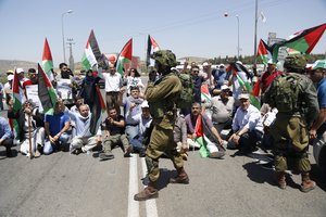 Palestinians protestors hold national flags during protest in solidarity with Palestinian prisoners on hunger strike in Israeli jails, near the settlement of Shavei Shamron near the West Bank city of Nablus, Tuesday, May 16, 2017.